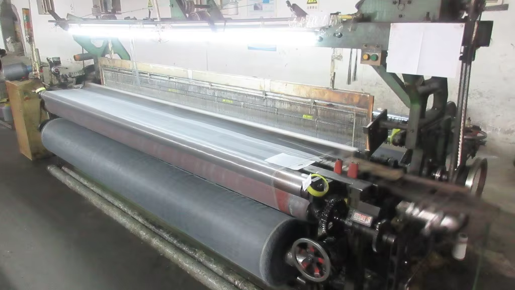 Screen mesh running through weaving equipment in a production workshop